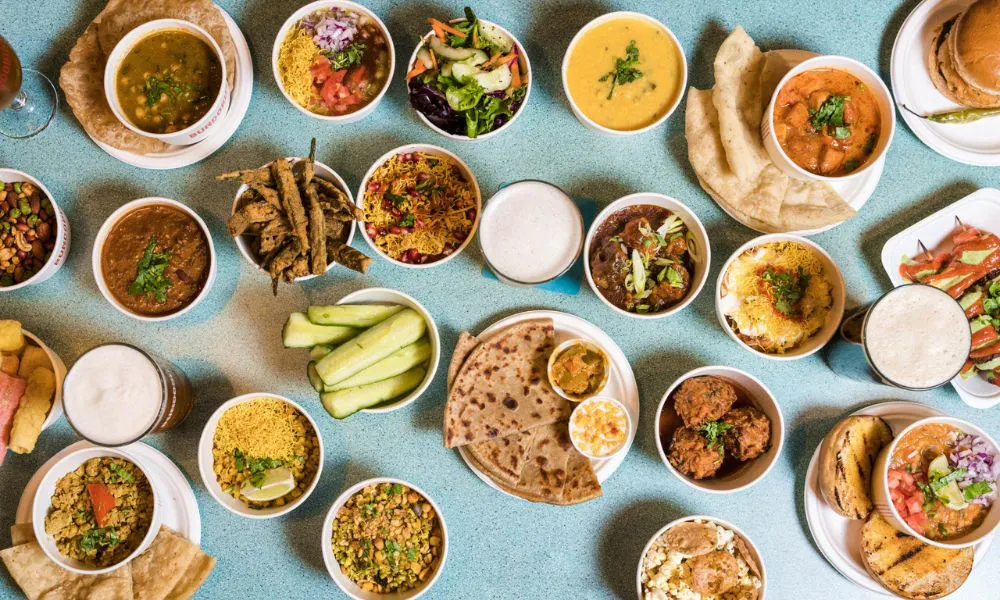 Indian small plates, curries and sides on blue table