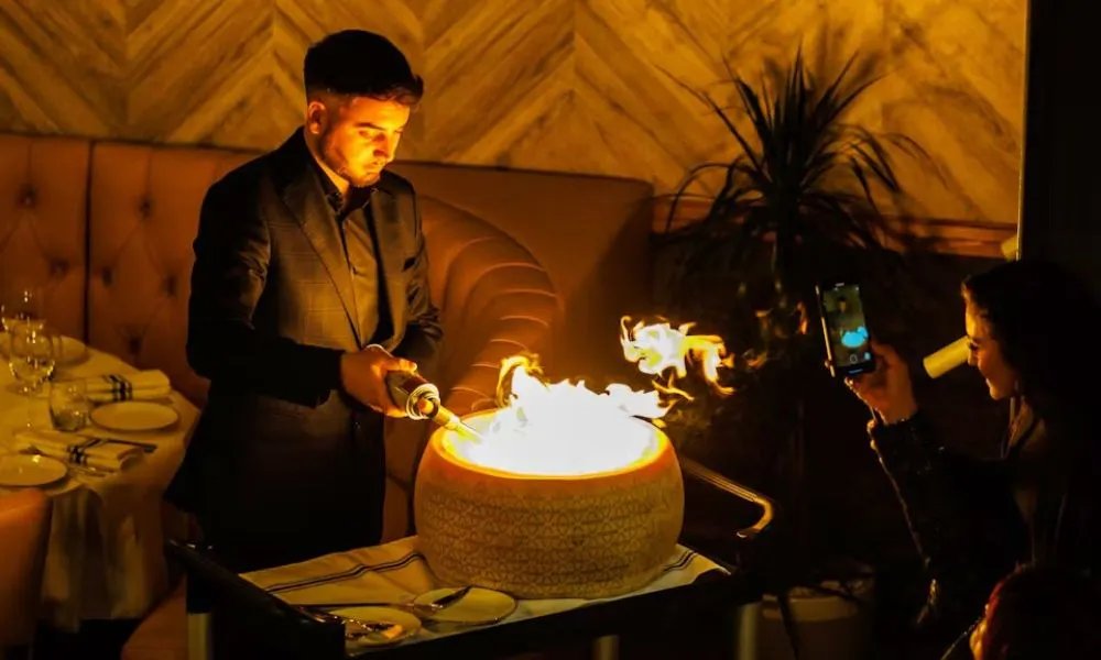 pasta being made at a table in a cheese wheel with fire