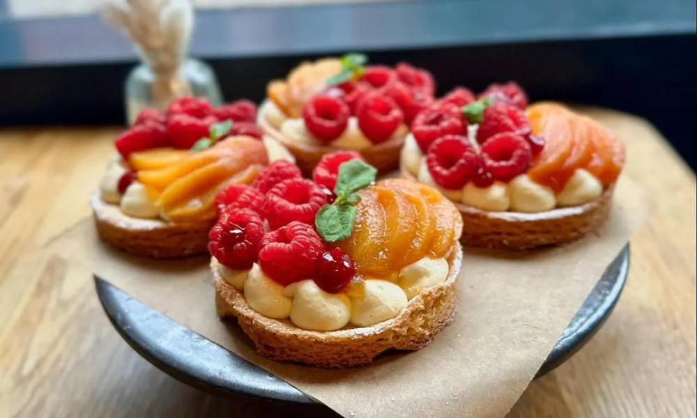 selection of tarts topped with cream and fruit