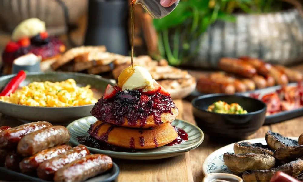 a selection of breakfast dishes and a stack of pancakces