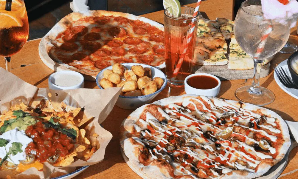 a selection of pizzas and drinks on a table