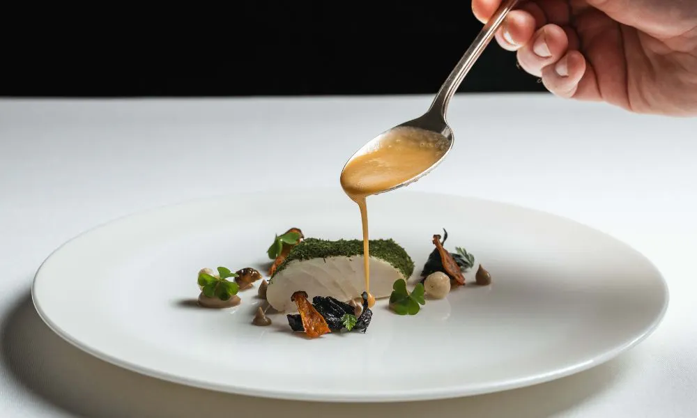 hand pouring sauce on dish