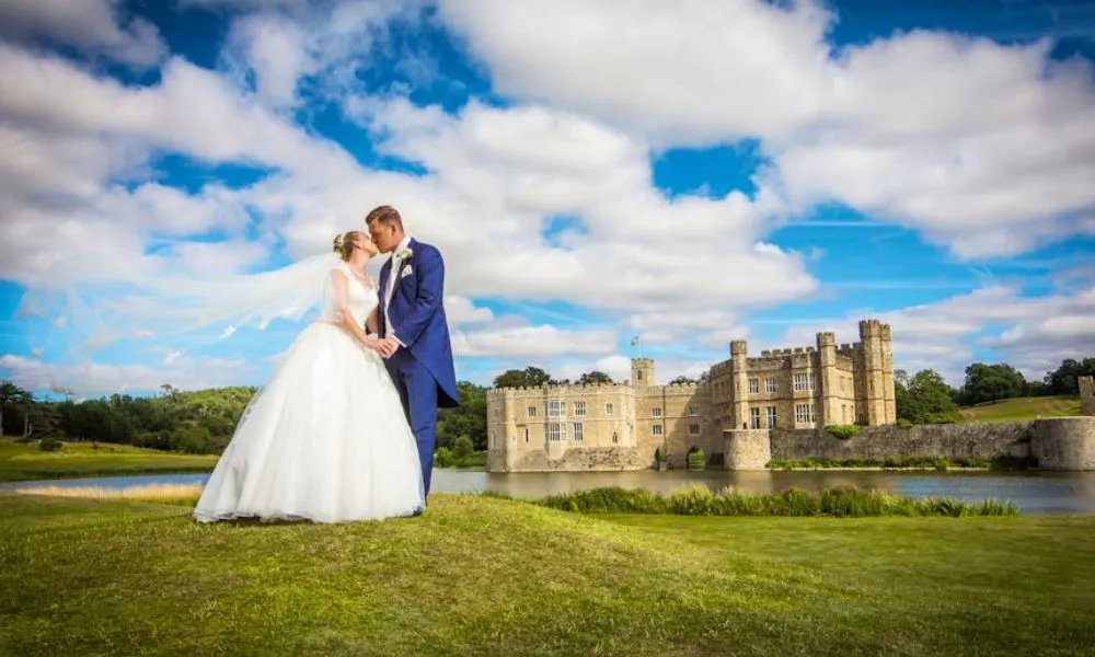 Bride and groom kiss with Leeds Castle in the background