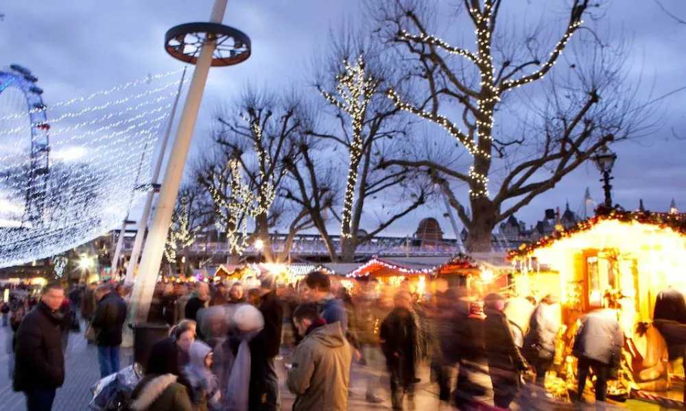 market huts with lights behind blurred group of people