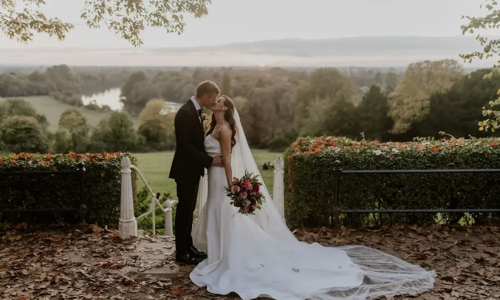 newly weds kiss with orange leaves and a park behind