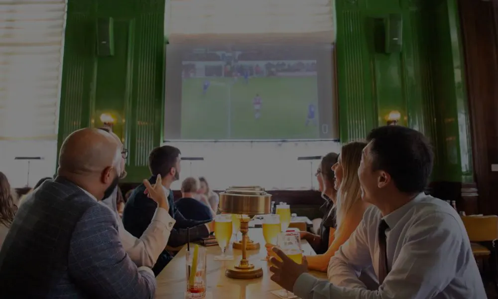 football fans watching the big screen with pints of beer