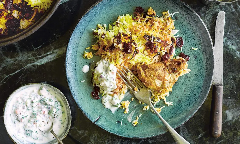 plate of curry with rice and yogurt dip