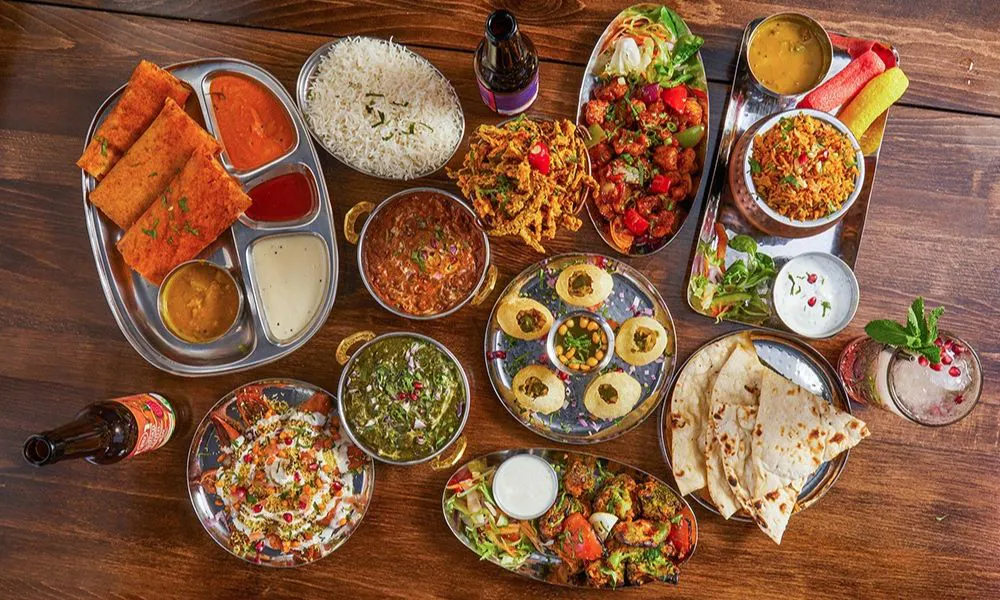 array of indian plates of curry rice and snacks