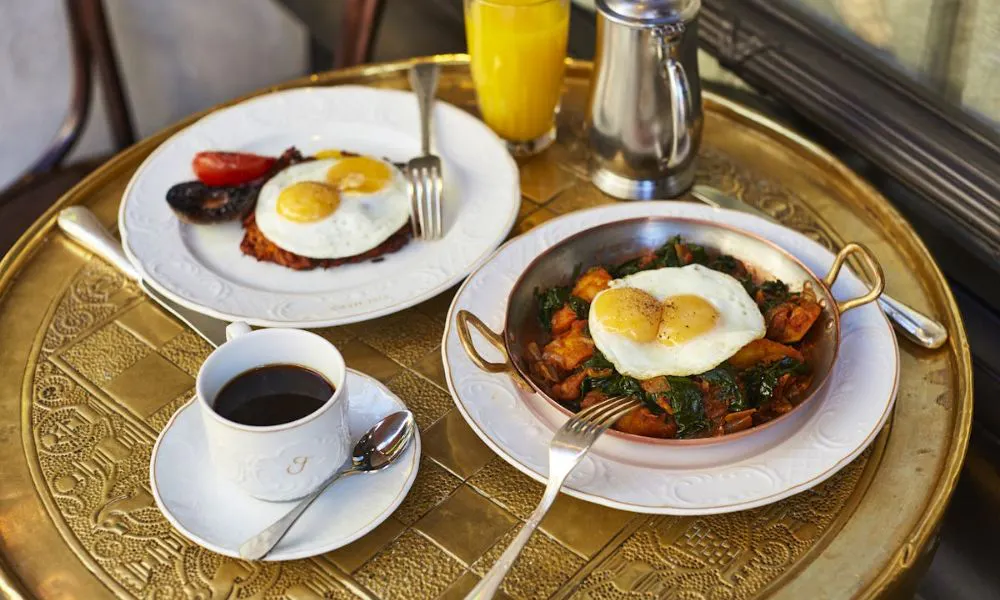 gold table with shaksouka, eggs, and black coffee
