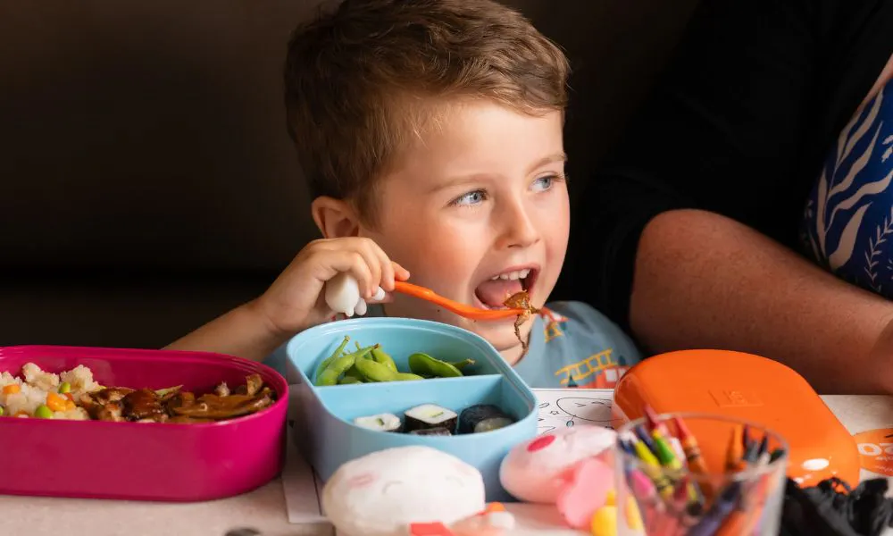 a child eating a kids bento box at yo sushi