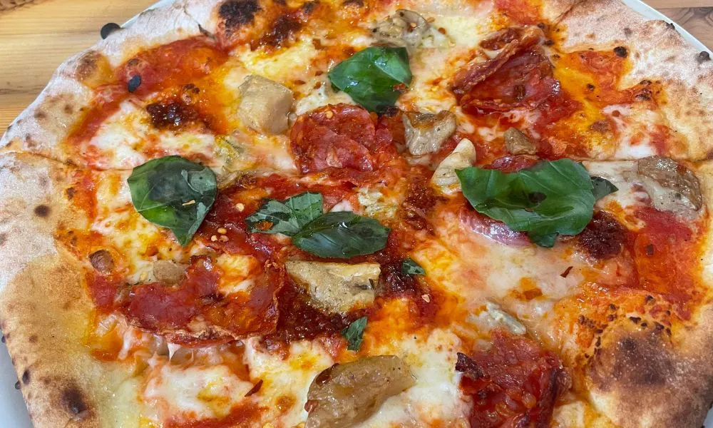 a pepperoni pizza topped with basil