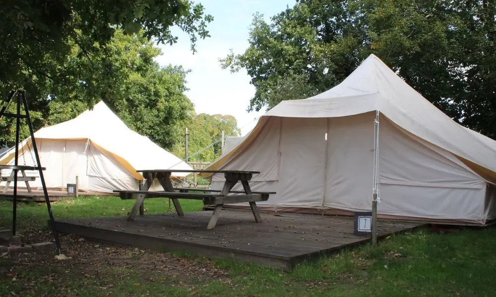 two large bell tents with wooden benches