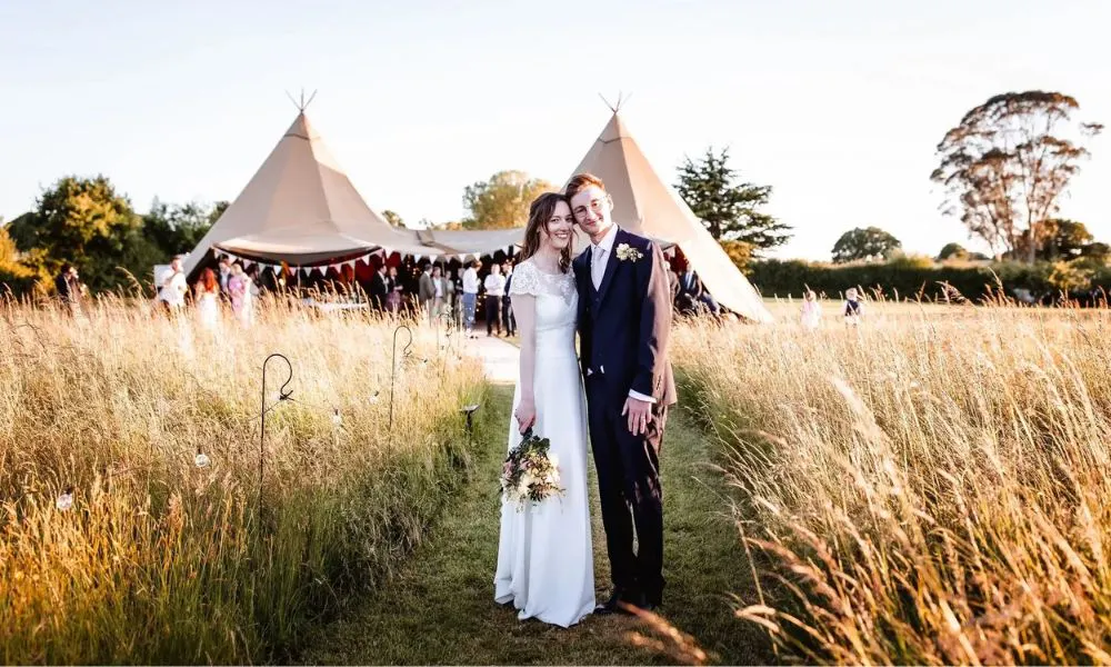 couple posing for a picture in front of wedding marquee
