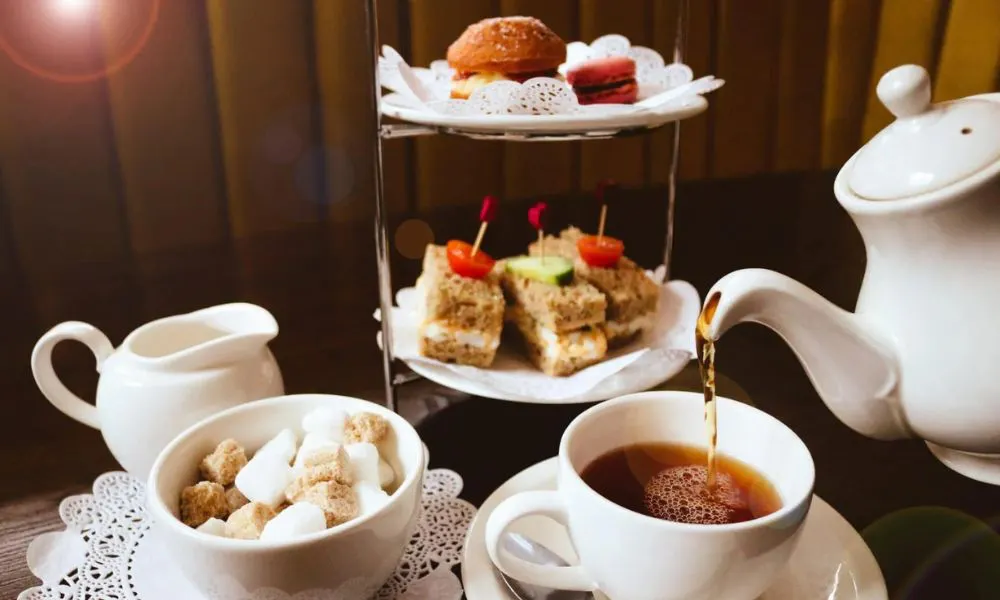 a stand of cakes and someone pouring a cup of tea