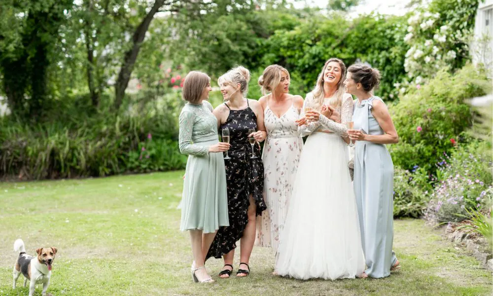 A bride and bridesmaids taking photos with a dog