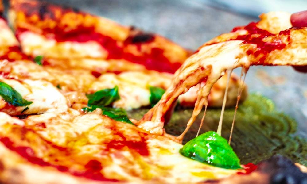 someone picking up a slice of pizza