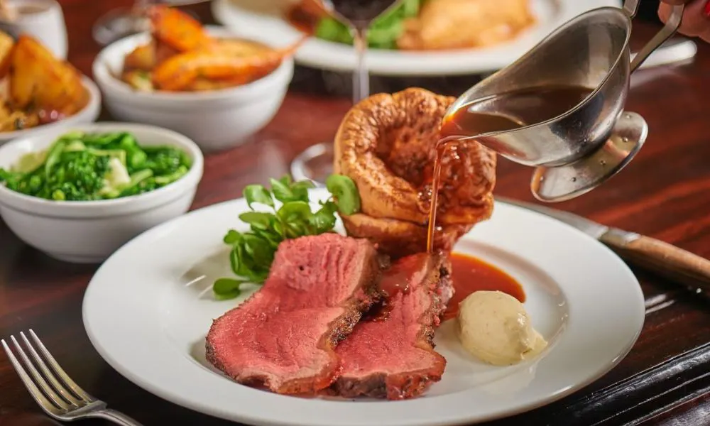 someone pouring gravy on roast beef