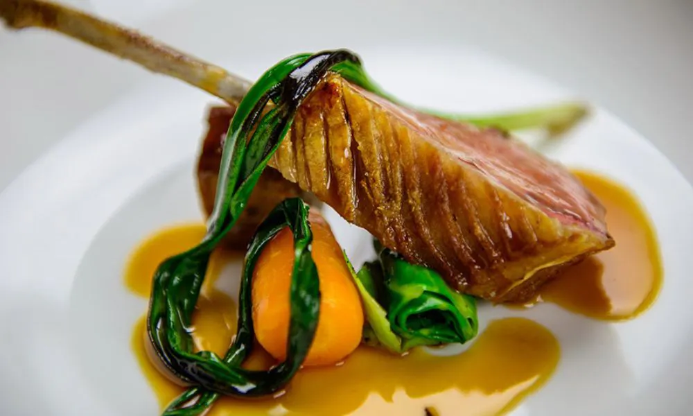 chop with wilted greens draped over on white plate