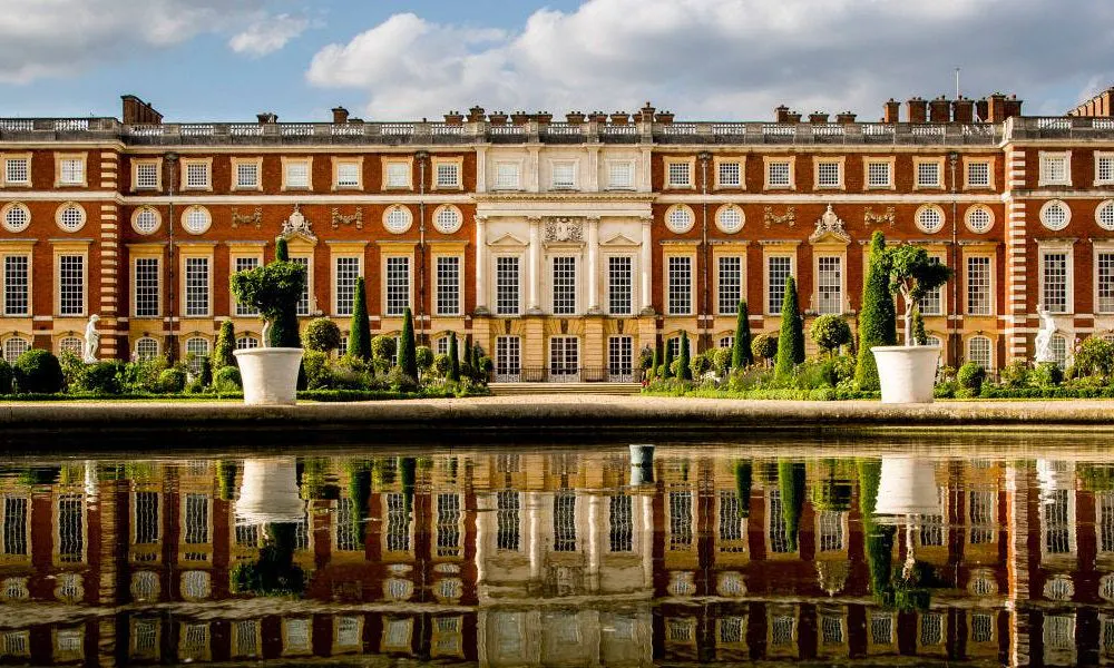 Large redbrick palace reflected in fountain water