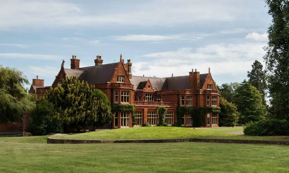 red brick manor house with ivy and trees