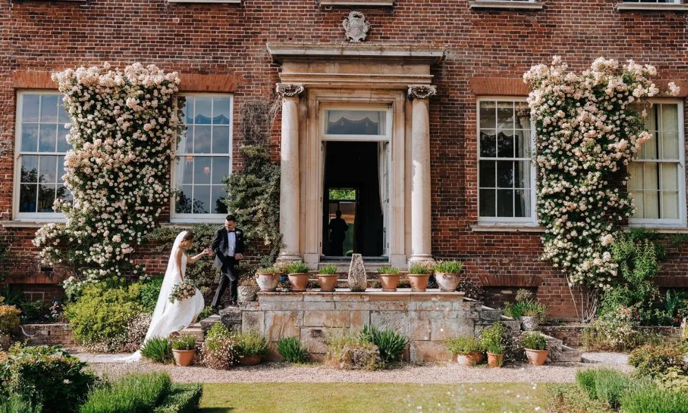 bride and groom head up steps into grand house