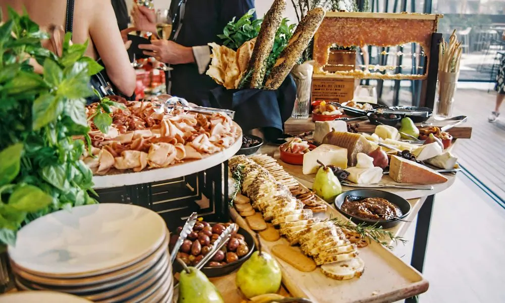 buffet table with sliced ham, meat, cheese, and fruit
