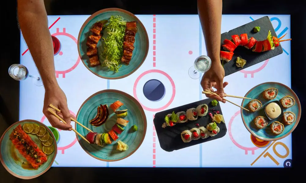 people eating sushi on an air hockey table