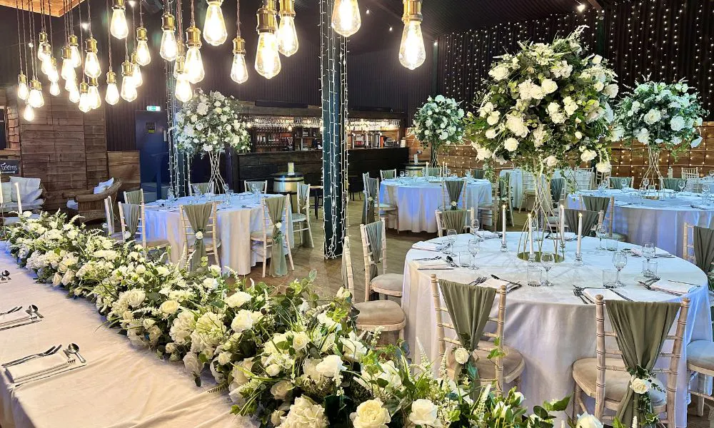 a wedding breakfast set up decorated with bunches of white roses
