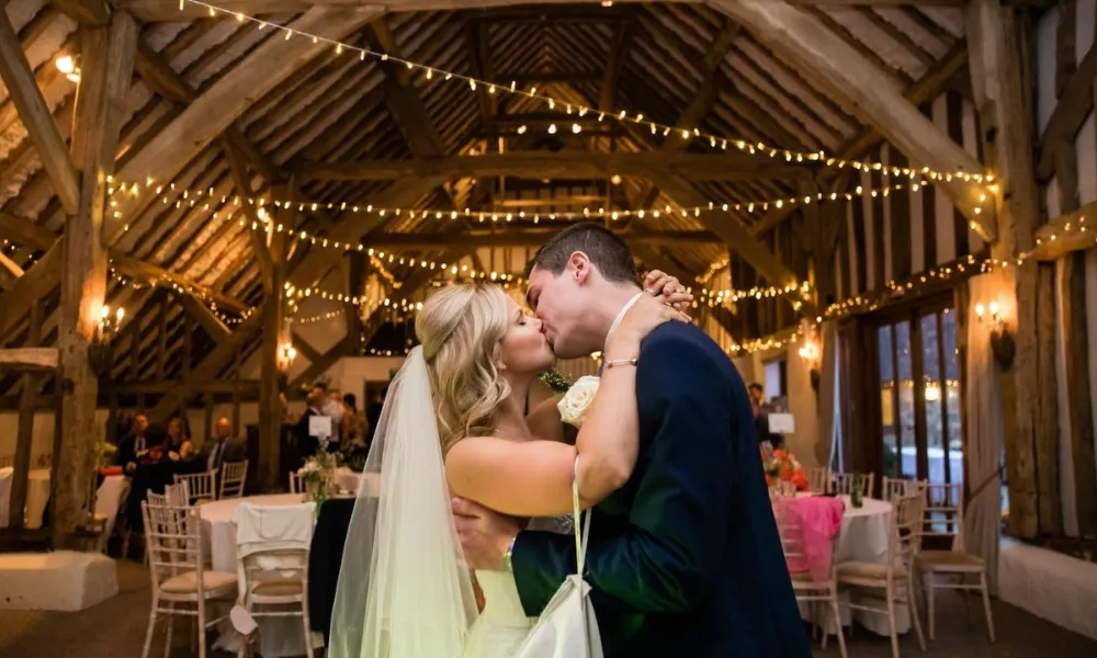 Bride and groom kissing in wedding barn