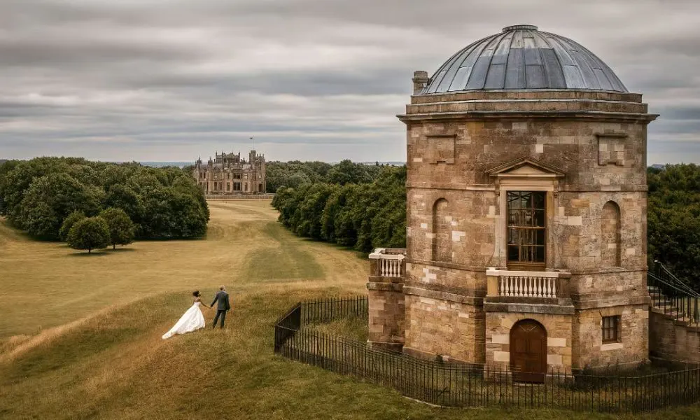a bride and groom walking through the grounds at Allerton castle