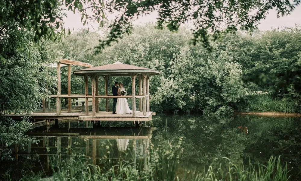 a bride and groom posing by a lake