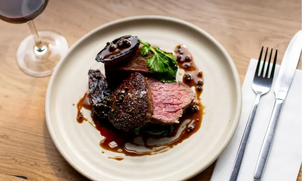 seared red meat on a plate with pickled walnut