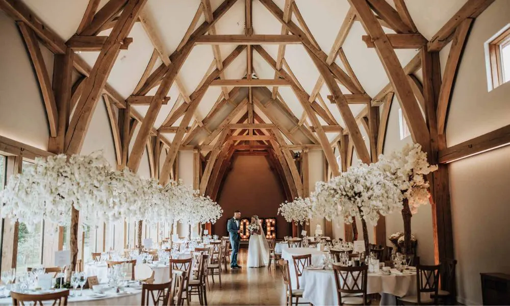 a couple on their wedding day in a barn surrounded by tables