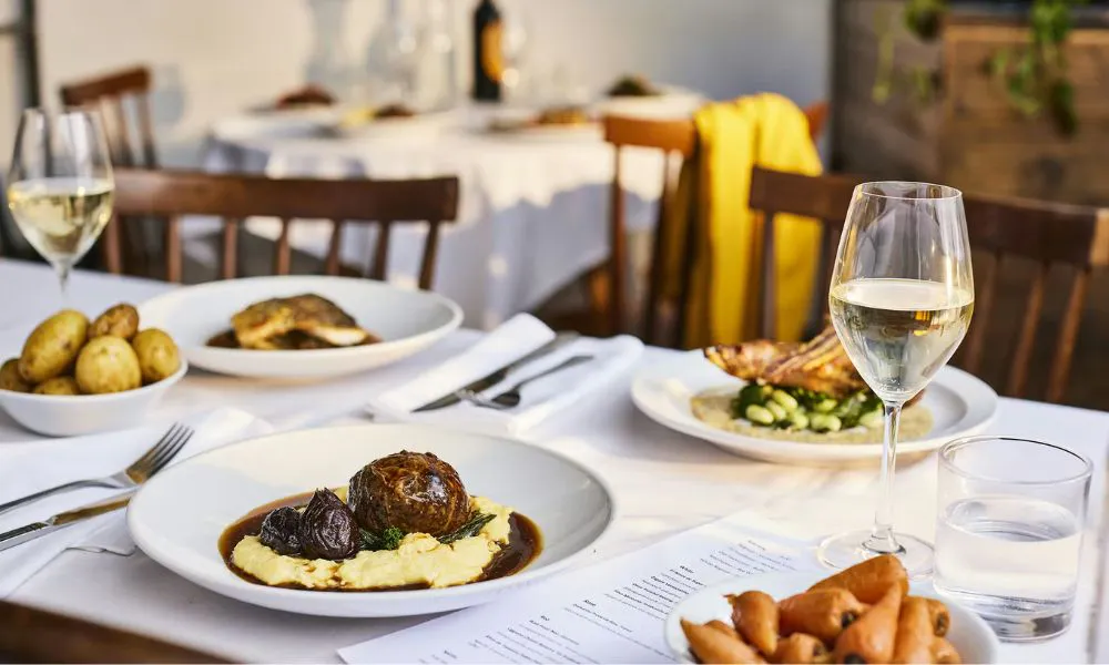 a table set with British classic dishes and glasses of wine