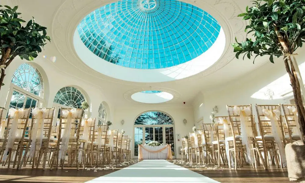 a striking Orangery with a domed glass skylight set up for a wedding ceremony