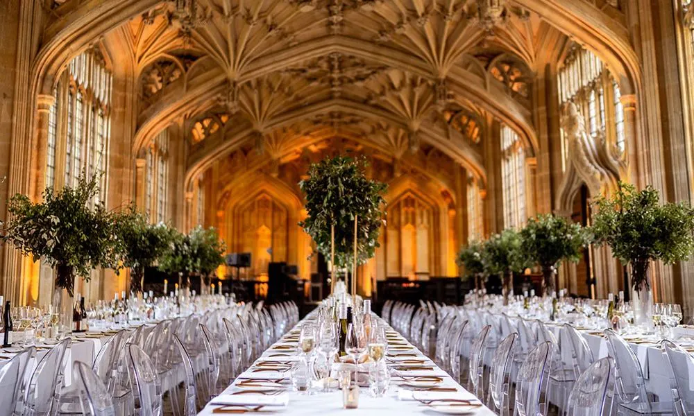 long banquet tables in library with white tablecloths and plant centrepieces