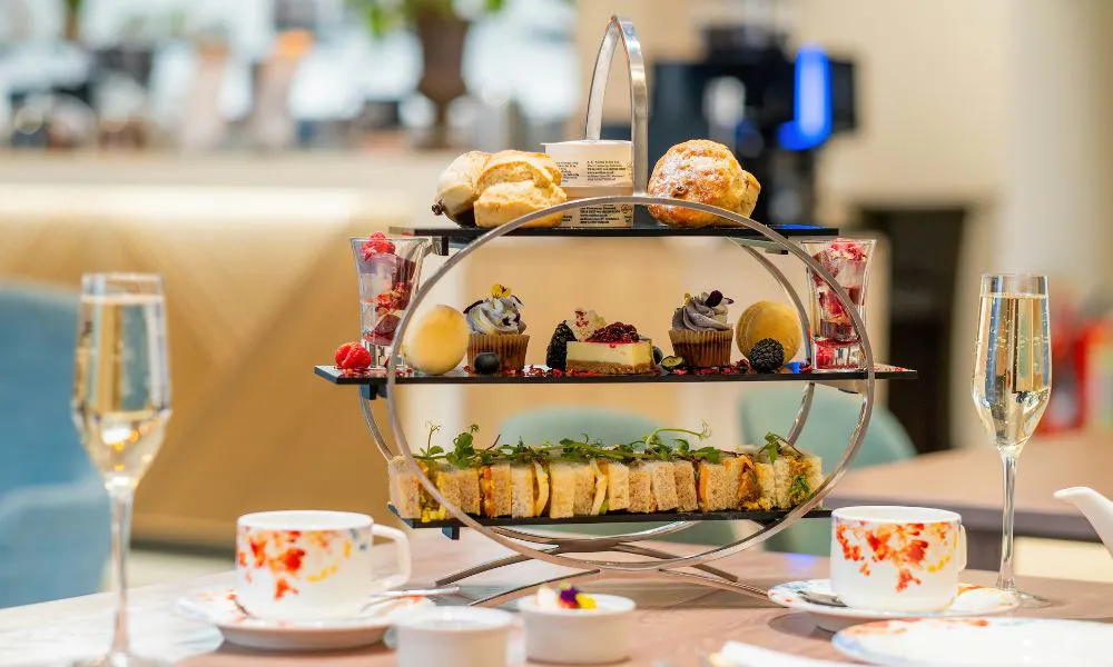 an oval three-tiered afternoon tea stand with glasses of prosecco
