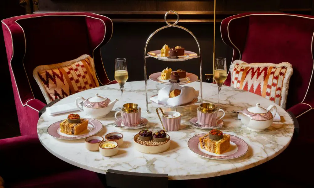 red velvet armchairs seated around a marble table set up for afternoon tea
