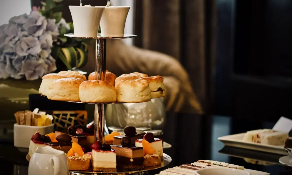 tray with cheesecakes, scones, and sandwiches