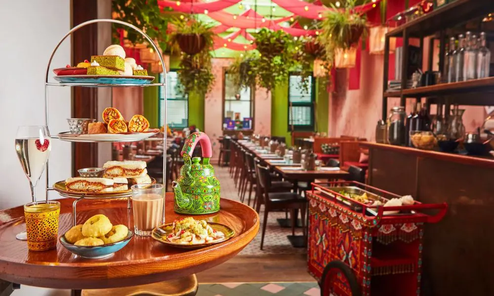 high chai with pot of tea and three tiers of indian snacks