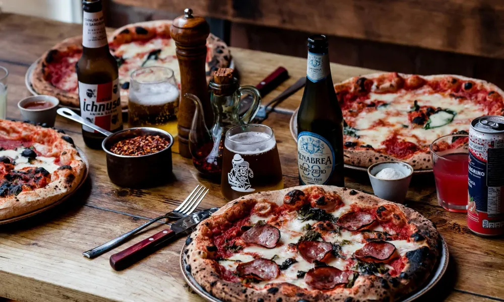 Neapolitan pizza and beer bottles on a table