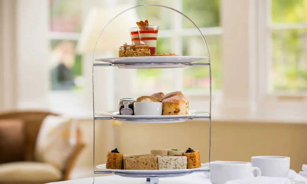 tea stand with sandwiches, sausage rolls, and scones