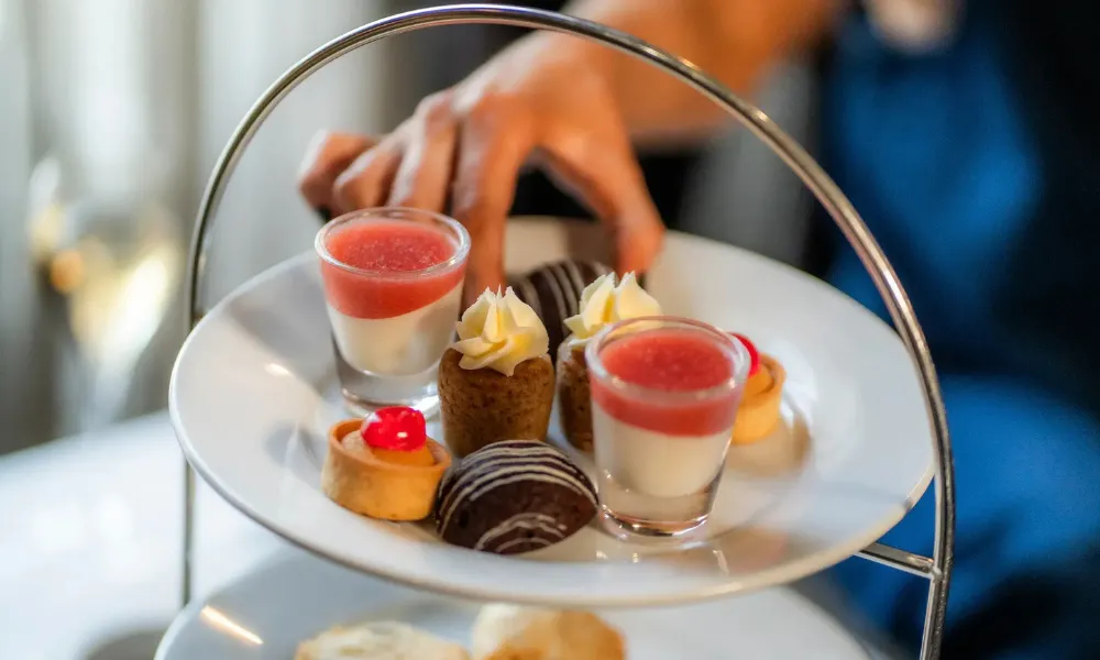 hand taking cake from afternoon tea stand