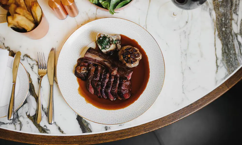 a steak dish on a marple-topped table