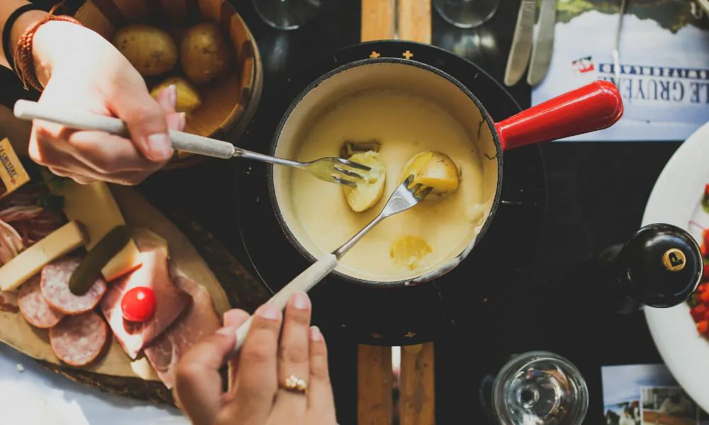 long forks dipping potatoes into saucepan