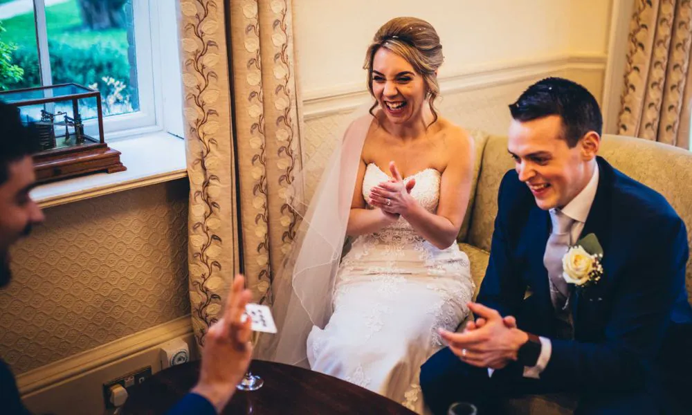 bride and groom clap at table in front of magician
