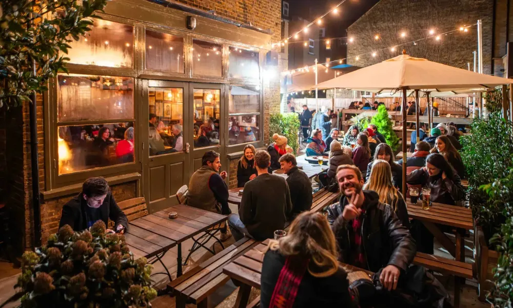 busy beer garden with string lights and umbrellas