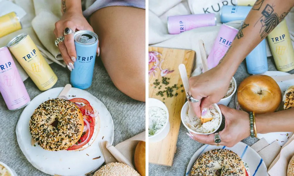 bagel with tomato and onion and canned drink on picnic blanket