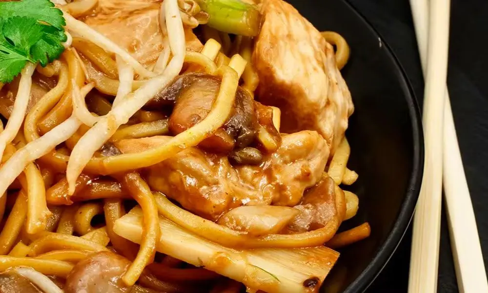 a bowl of noddles and some chopsticks