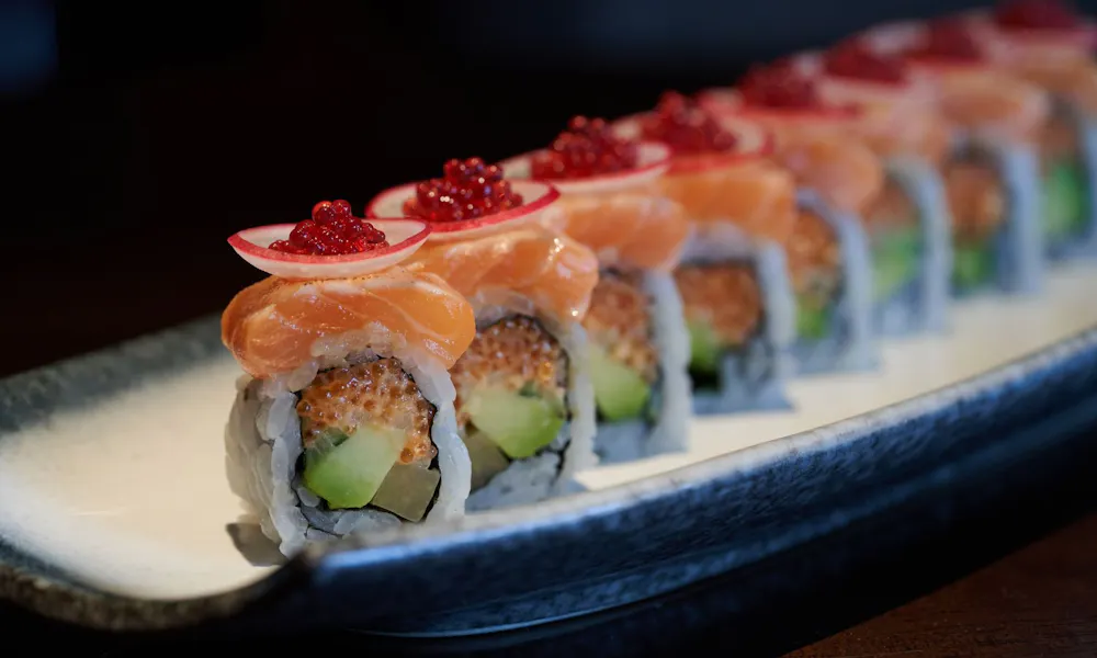 A platter of salmon-topped sushi with caviar on it